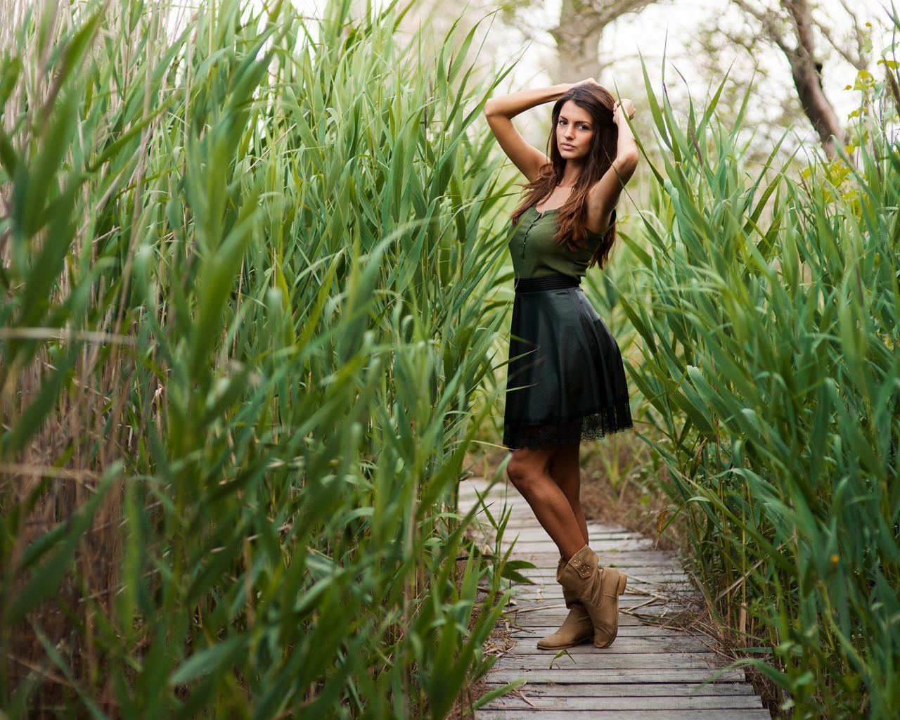Девушка на деревянной дорожке среди камышей