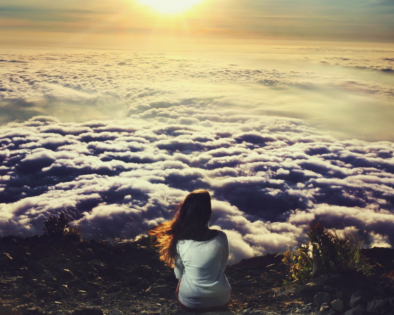 Девушка сидит и смотрит на облака