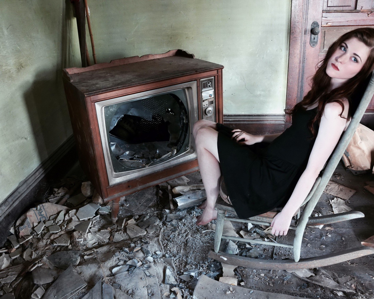 Девушка сидит у разбитого старого телевизора