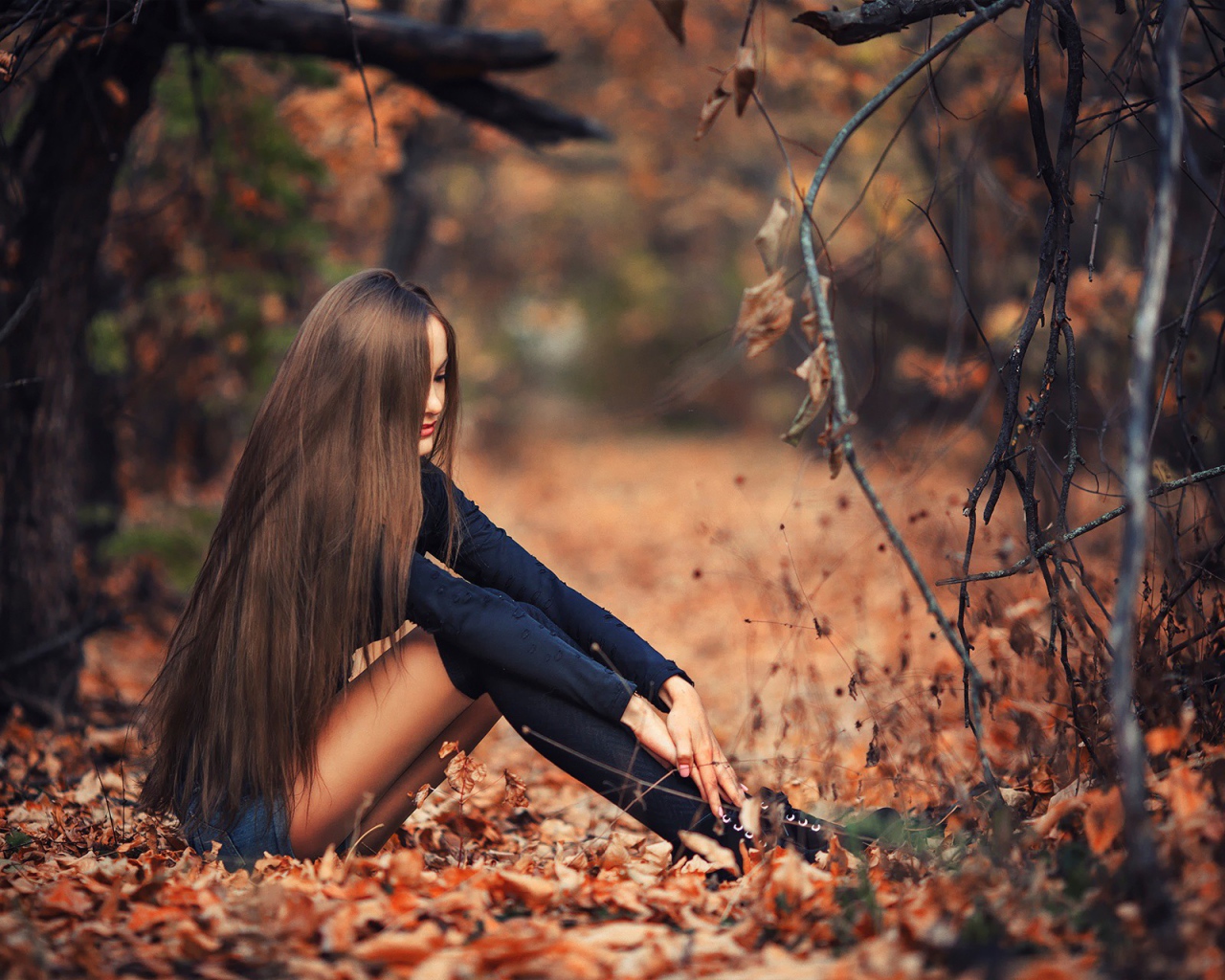 Девушка сидит на осенней листве