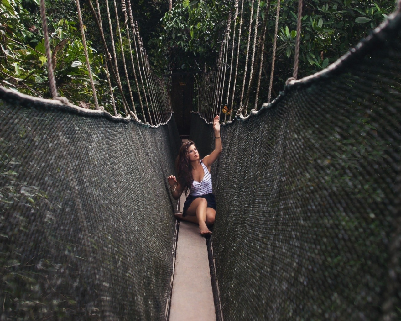 Девушка сидит на подвесном мосту