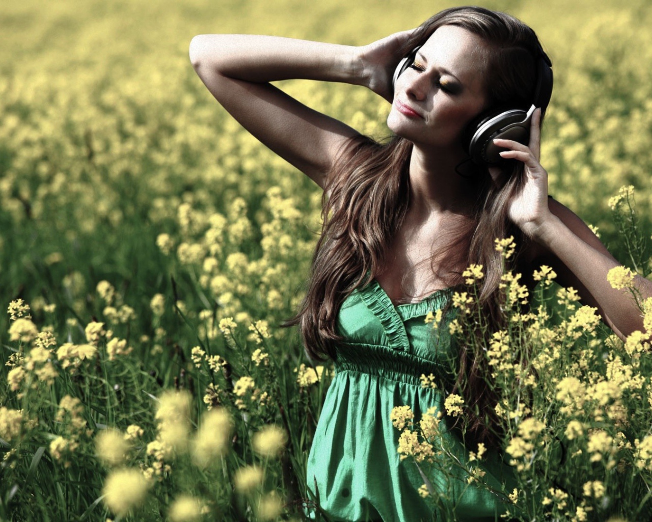 Девушка стоит среди цветов в наушниках