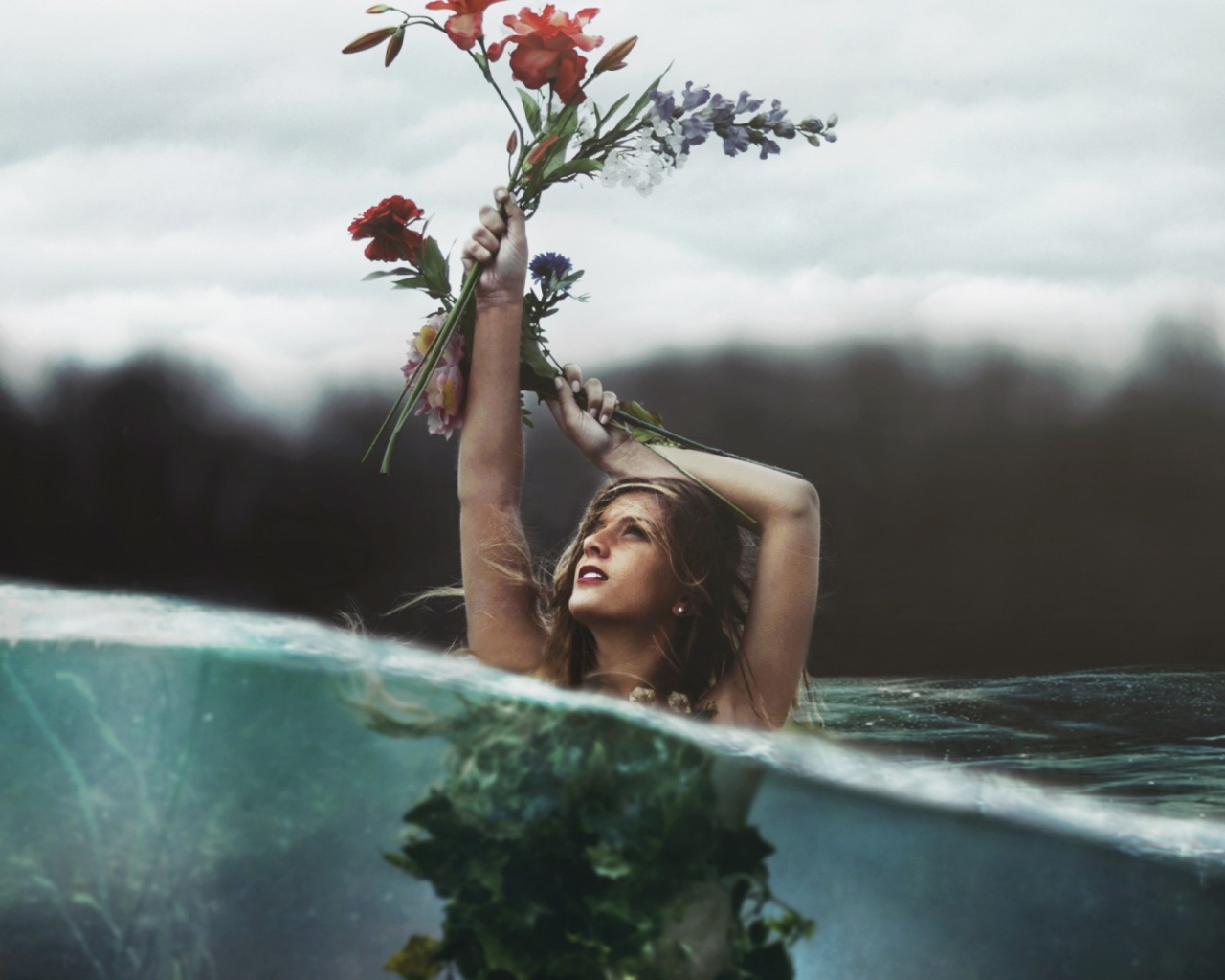 Девушка стоит в воде с букетом в руке
