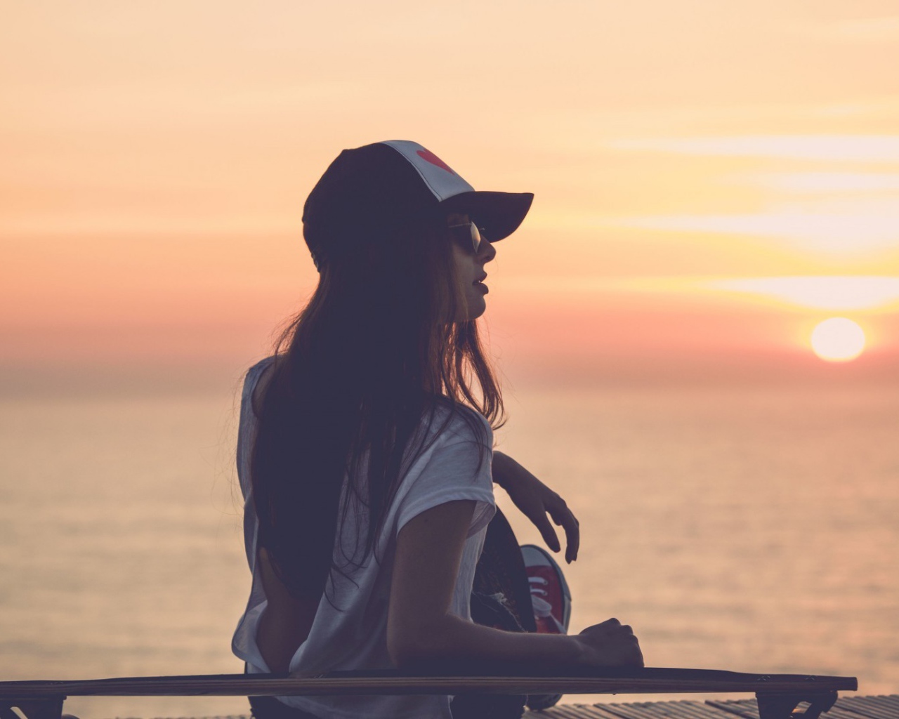 Девушка смотрит на закат на пляже