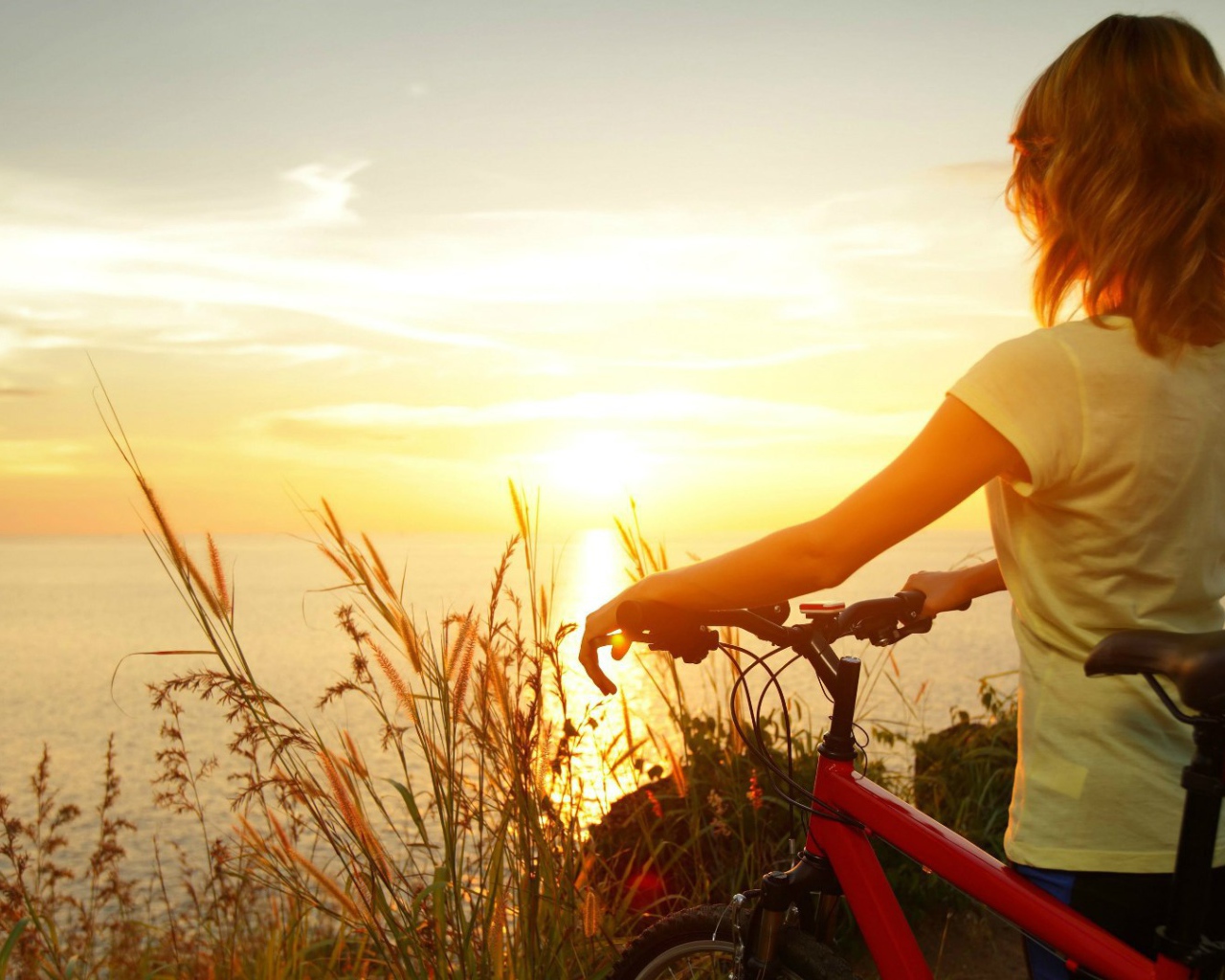 Девушка с велосипедом смотрит на закат