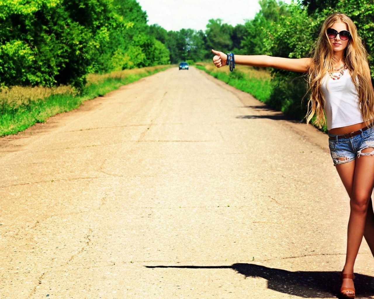 Девушка с чемоданом занимается автостопом