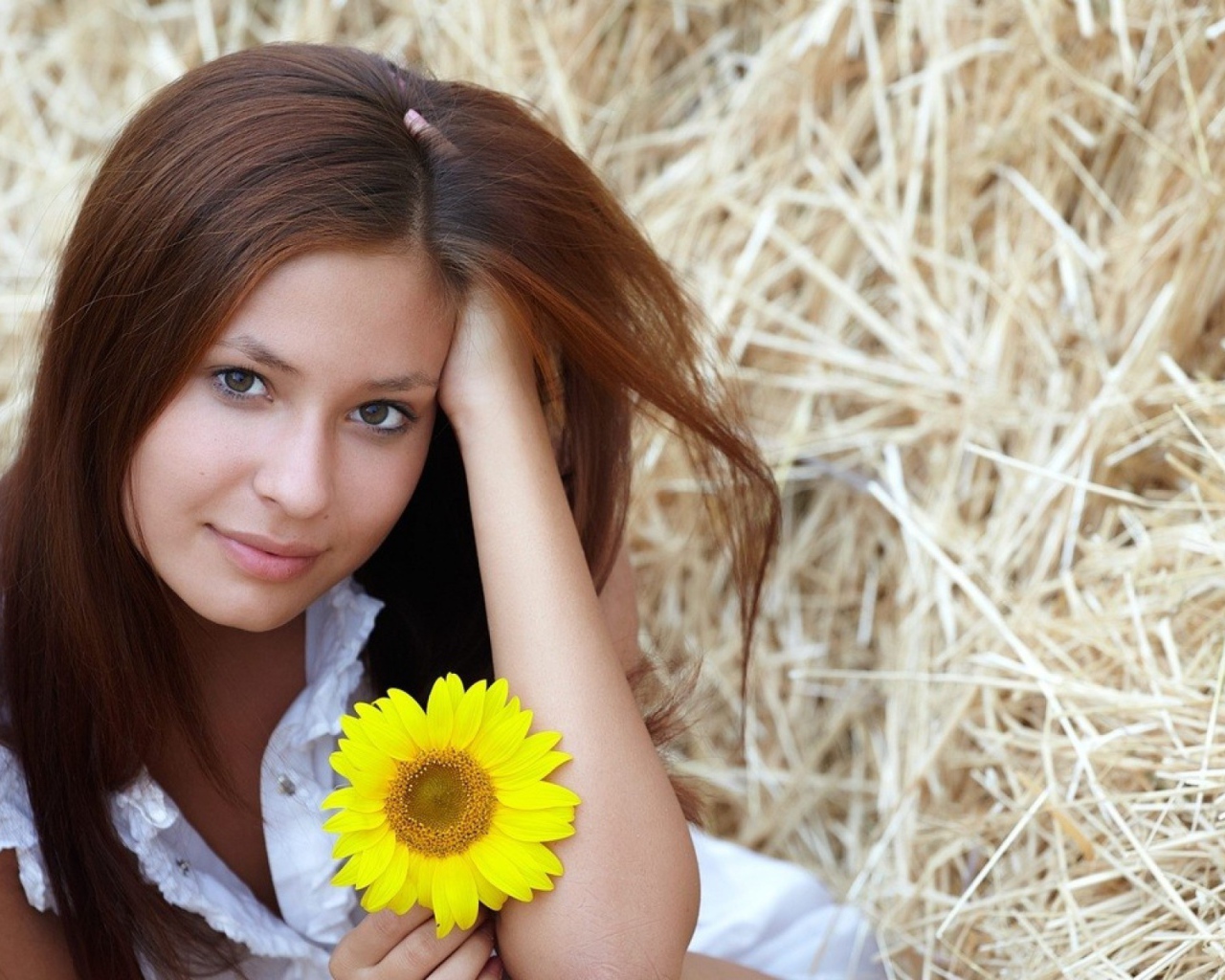 Девушка с желтым цветком сидит на сене