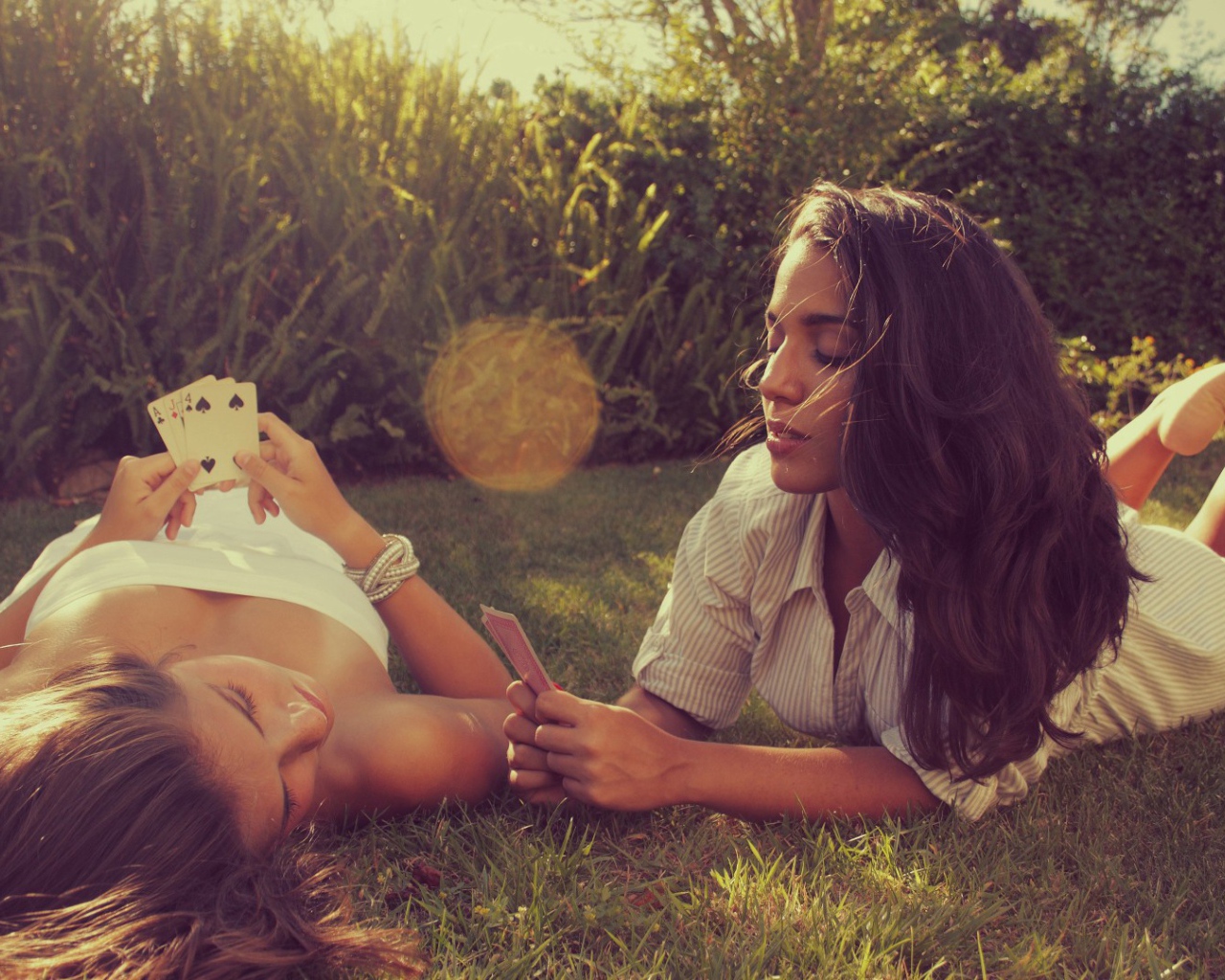 Девушки играют в карты на газоне