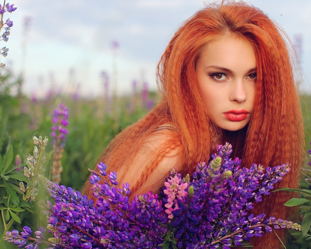 Длинноволосая рыжая девушка в поле лаванды