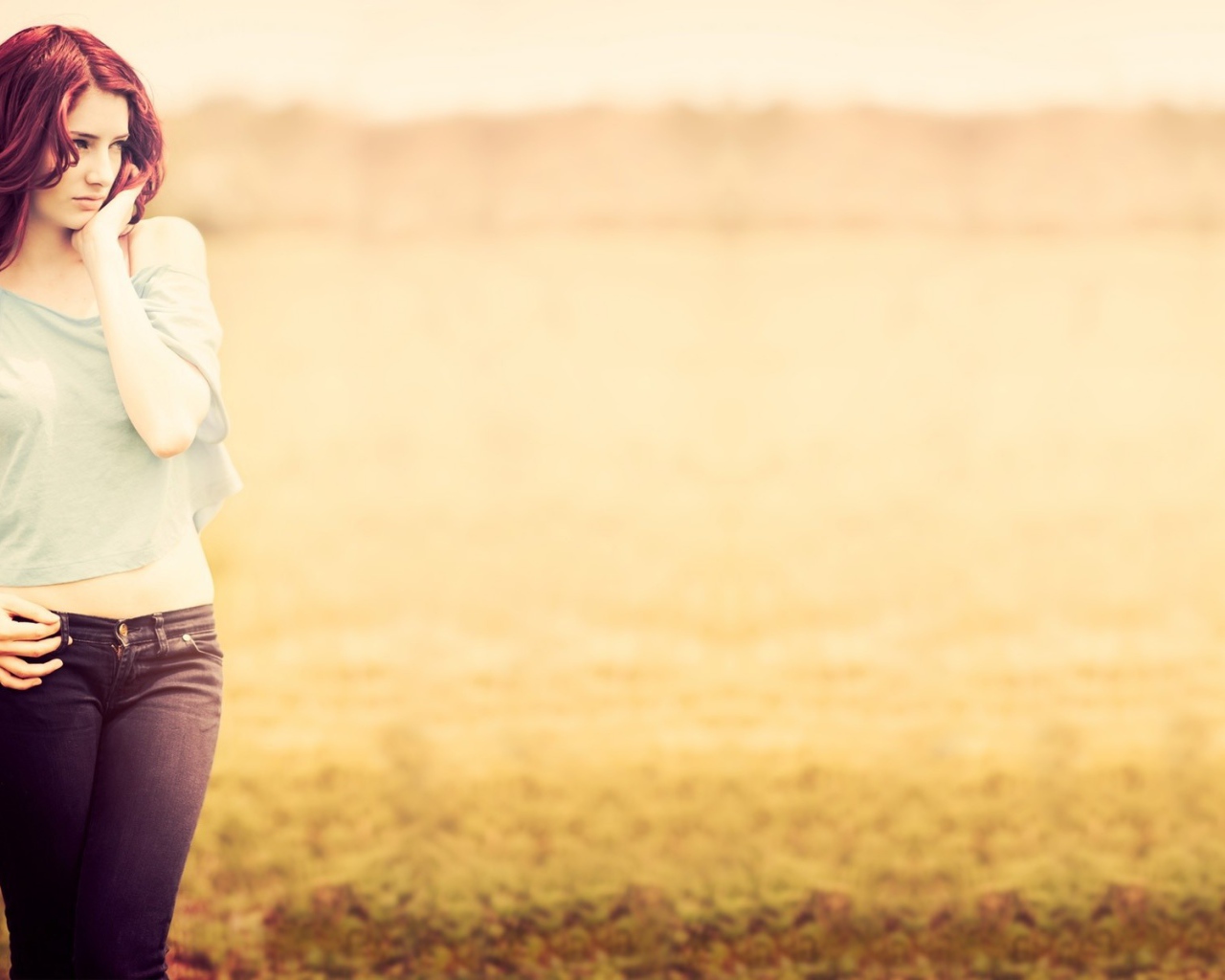 Рыжая девушка в джинсах и серой футболке