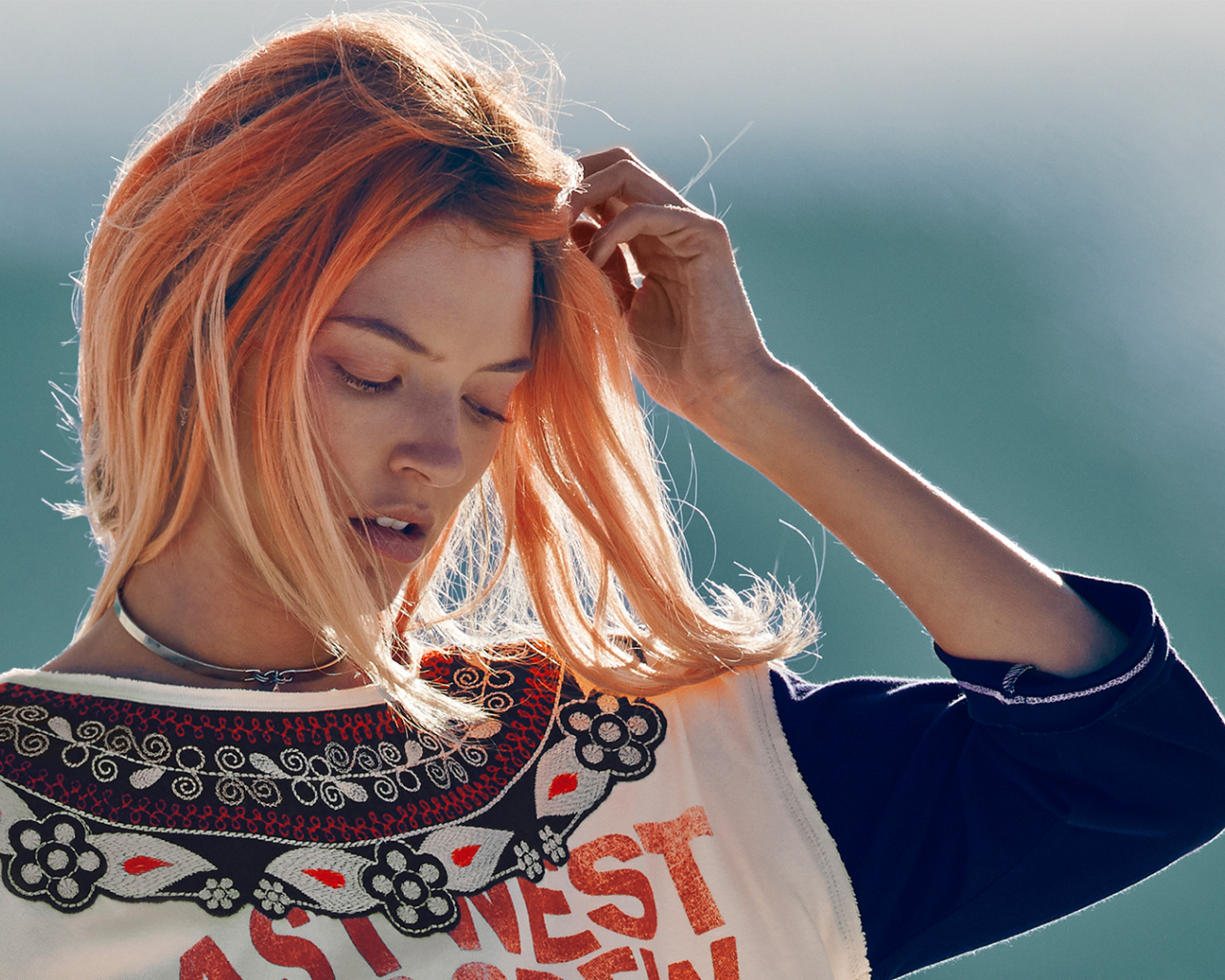 Рыжая девушка на ветру поправляет волосы