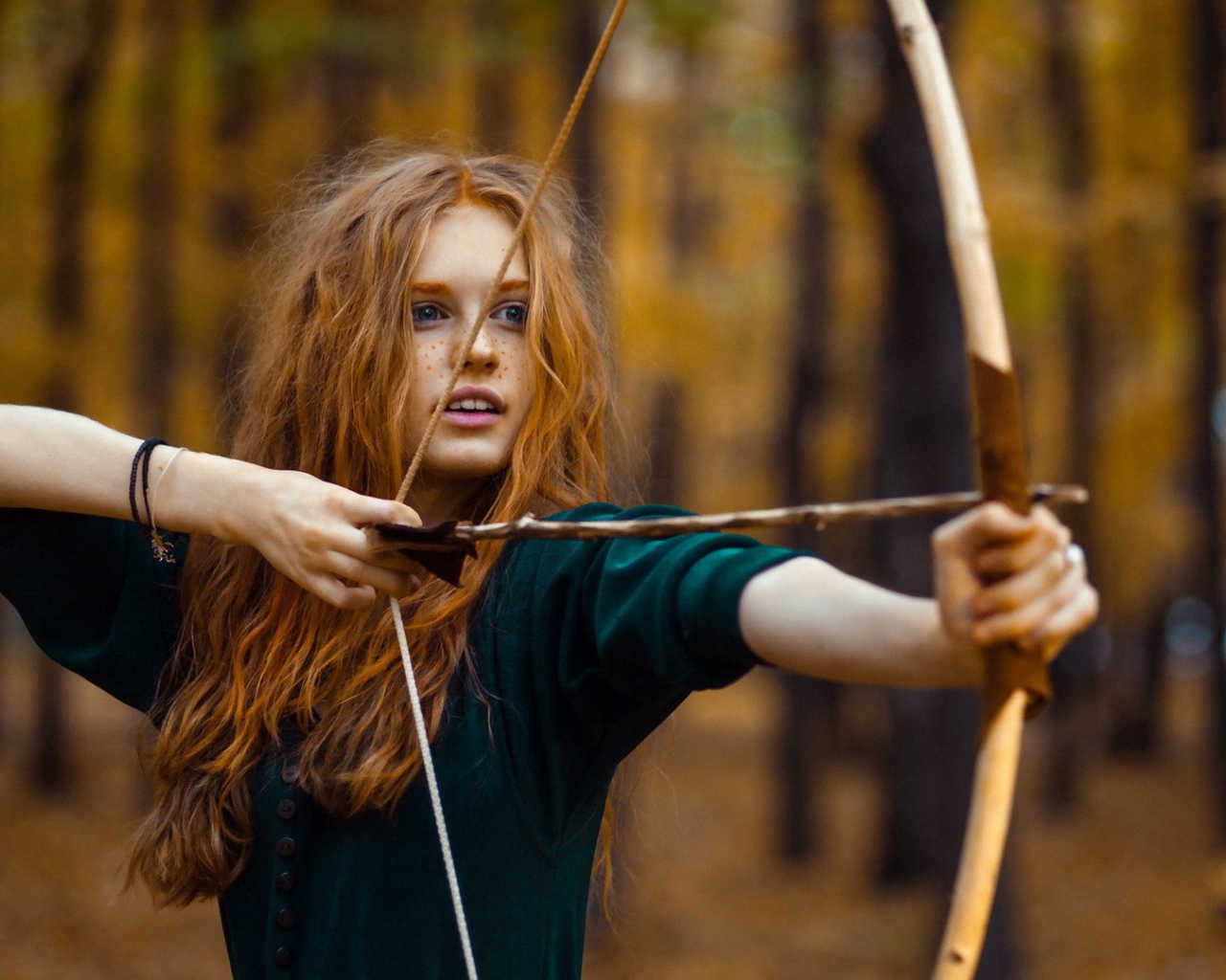 Рыжая девушка целится из лука