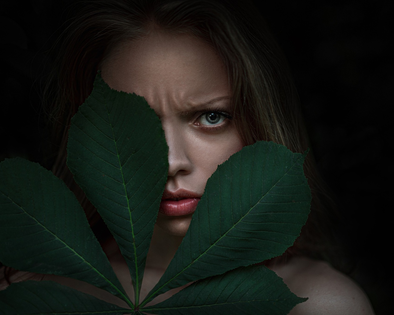 Девушка прикрыла лицо листьями каштана