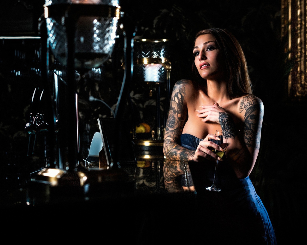 Татуированная девушка пьет вино в баре