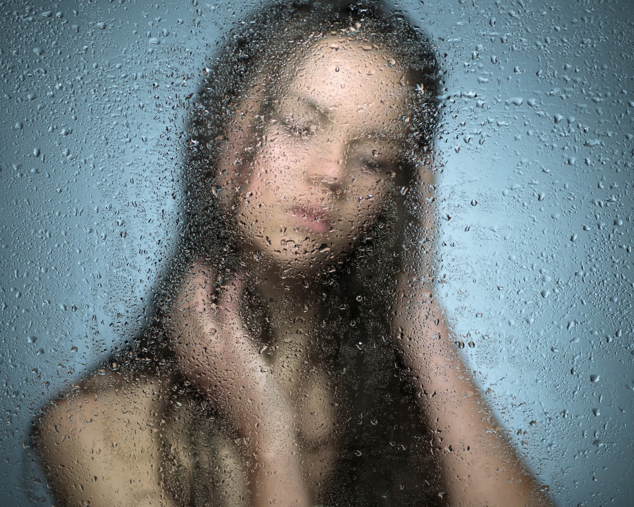 Девушка позади мокрого стекла