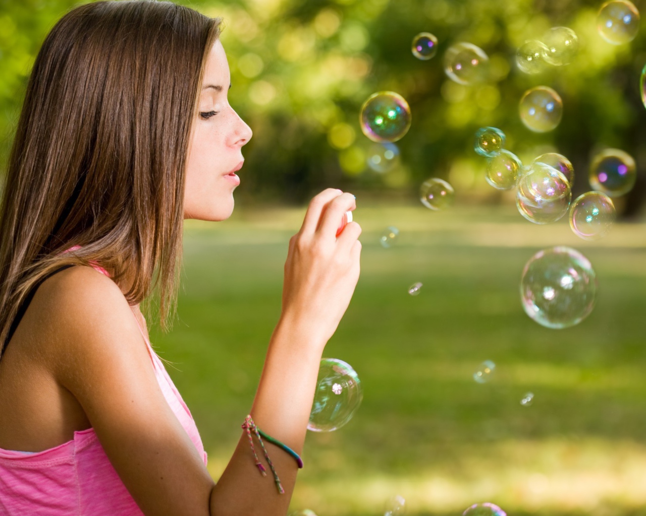 Девушка в розовой футболке запускает мыльные пузыри