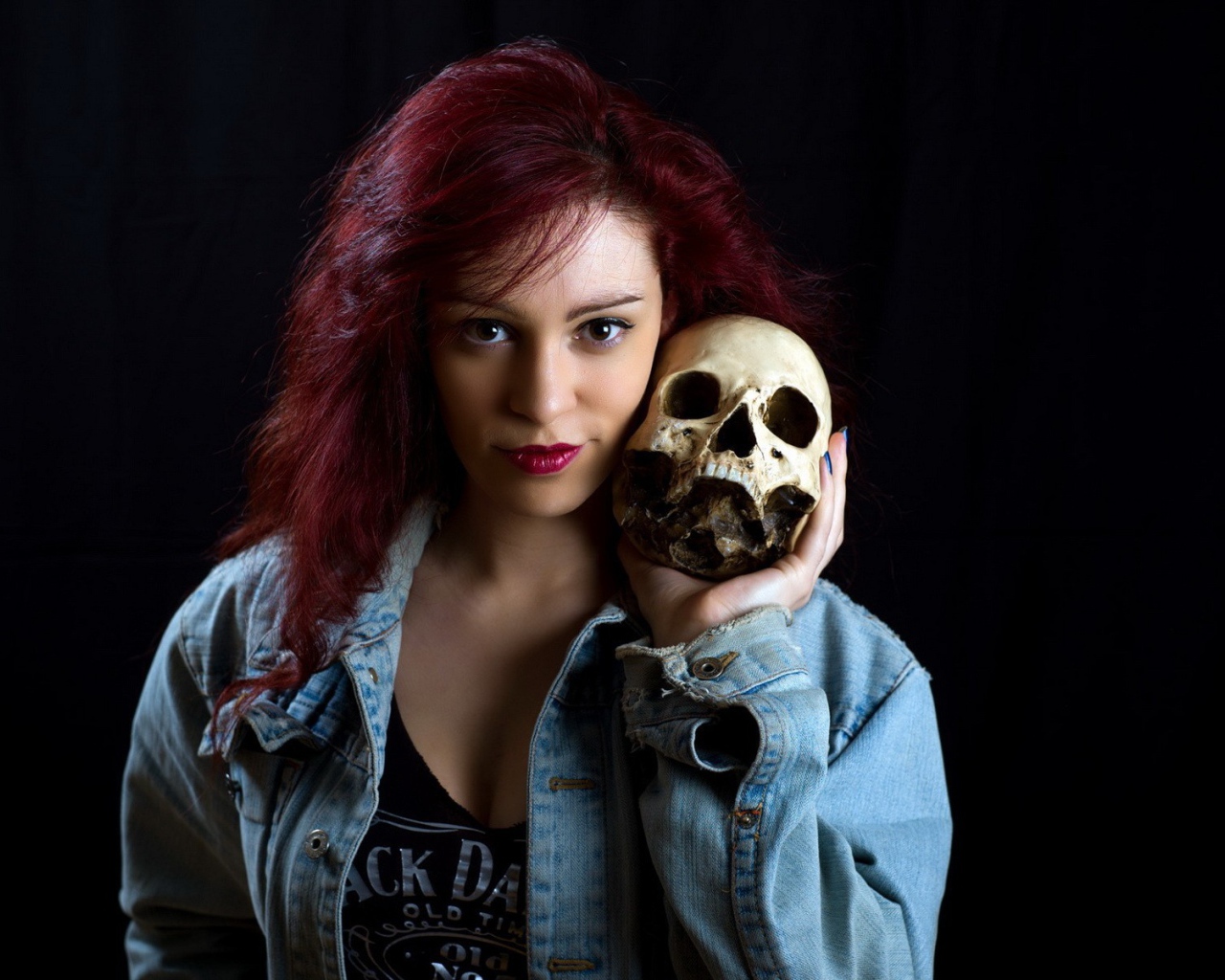 Девушка в джинсовой куртке держит череп на плече