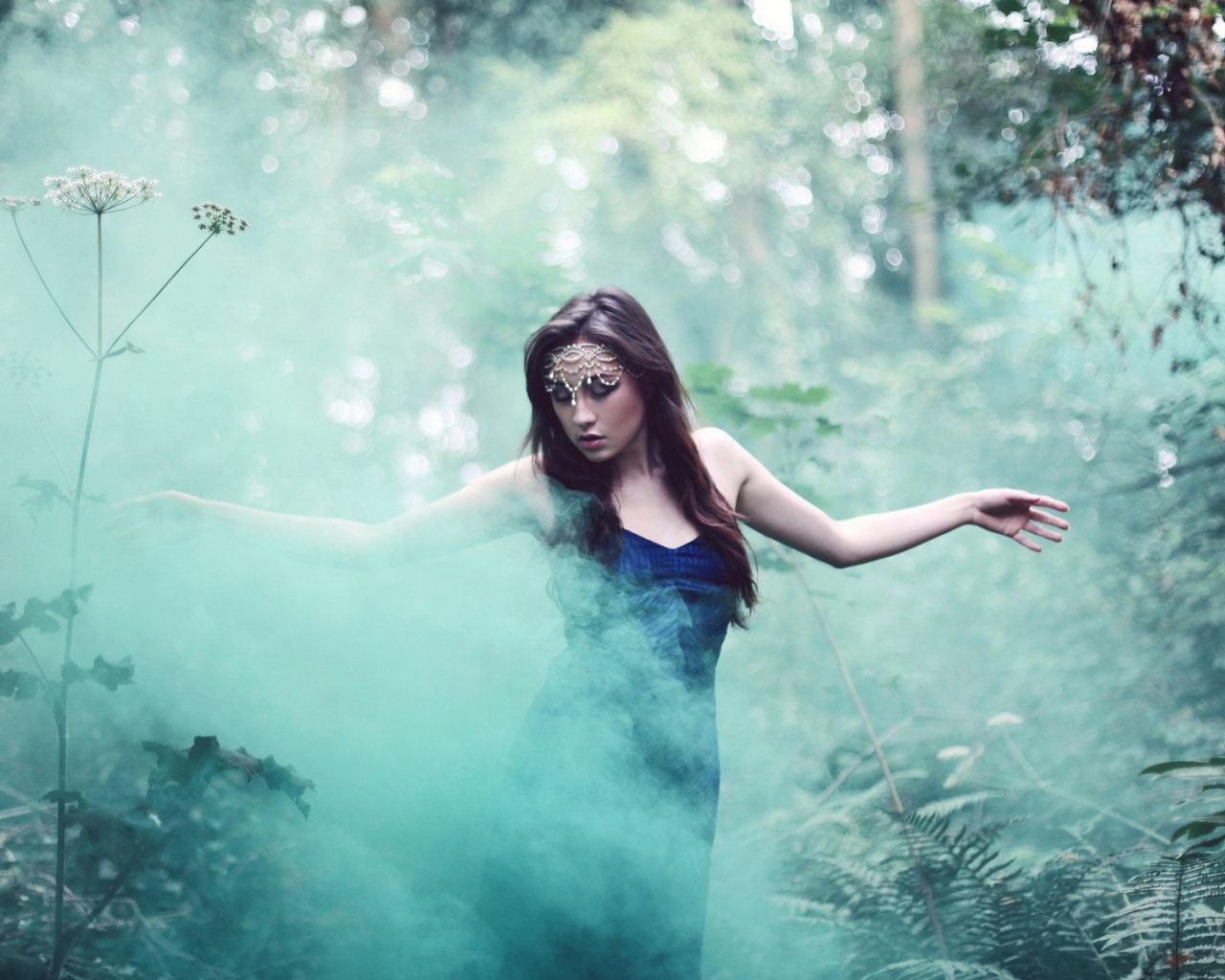 Девушка идет среди дыма по лесу