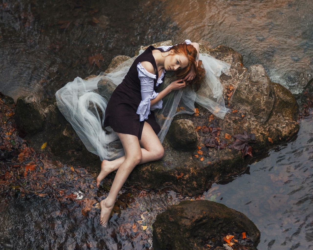 Девушка лежит на камне среди воды