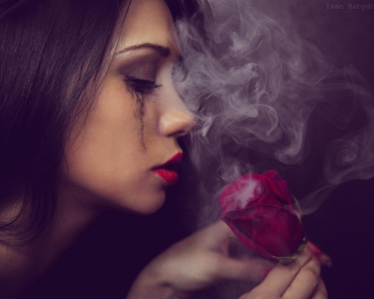 The girl looks at smoking rose