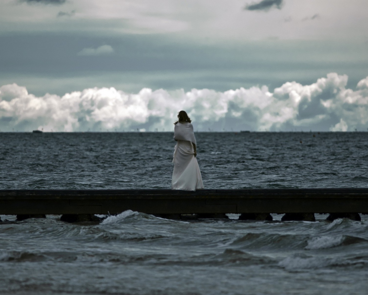 Девушка смотрит на свинцовые воды моря