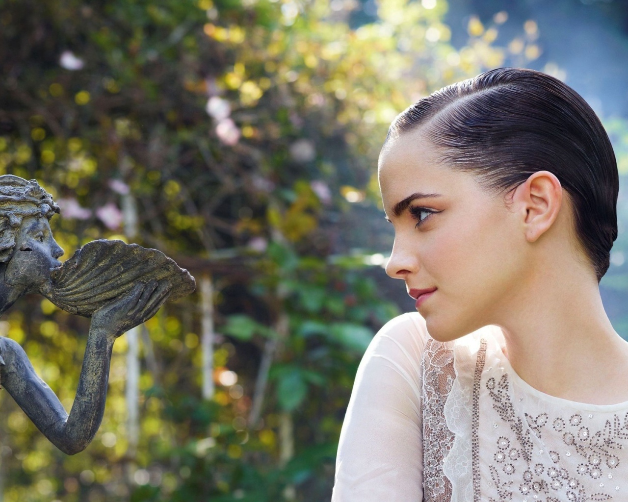 Девушка смотрит на скульптуру в саду