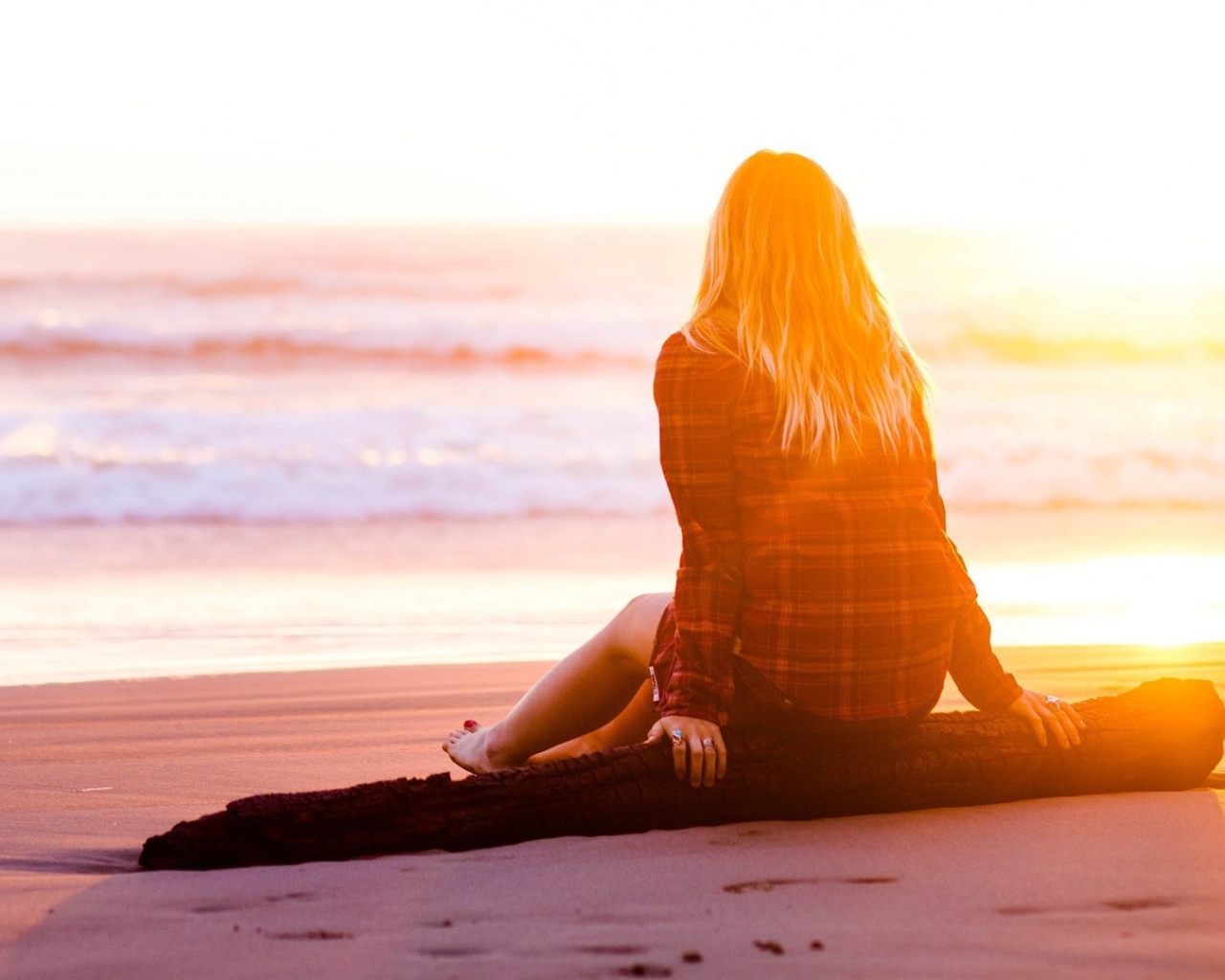 Девушка на сидит на пляже во время заката