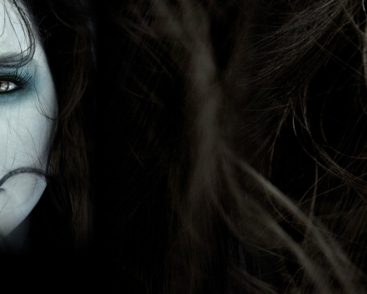 Лицо девушки среди волос на темном фоне