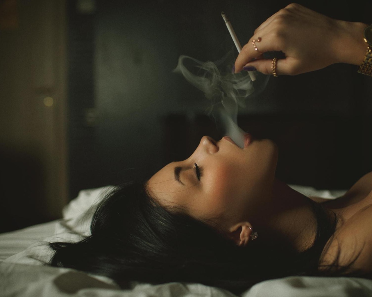 Девушка курит лежа в постели