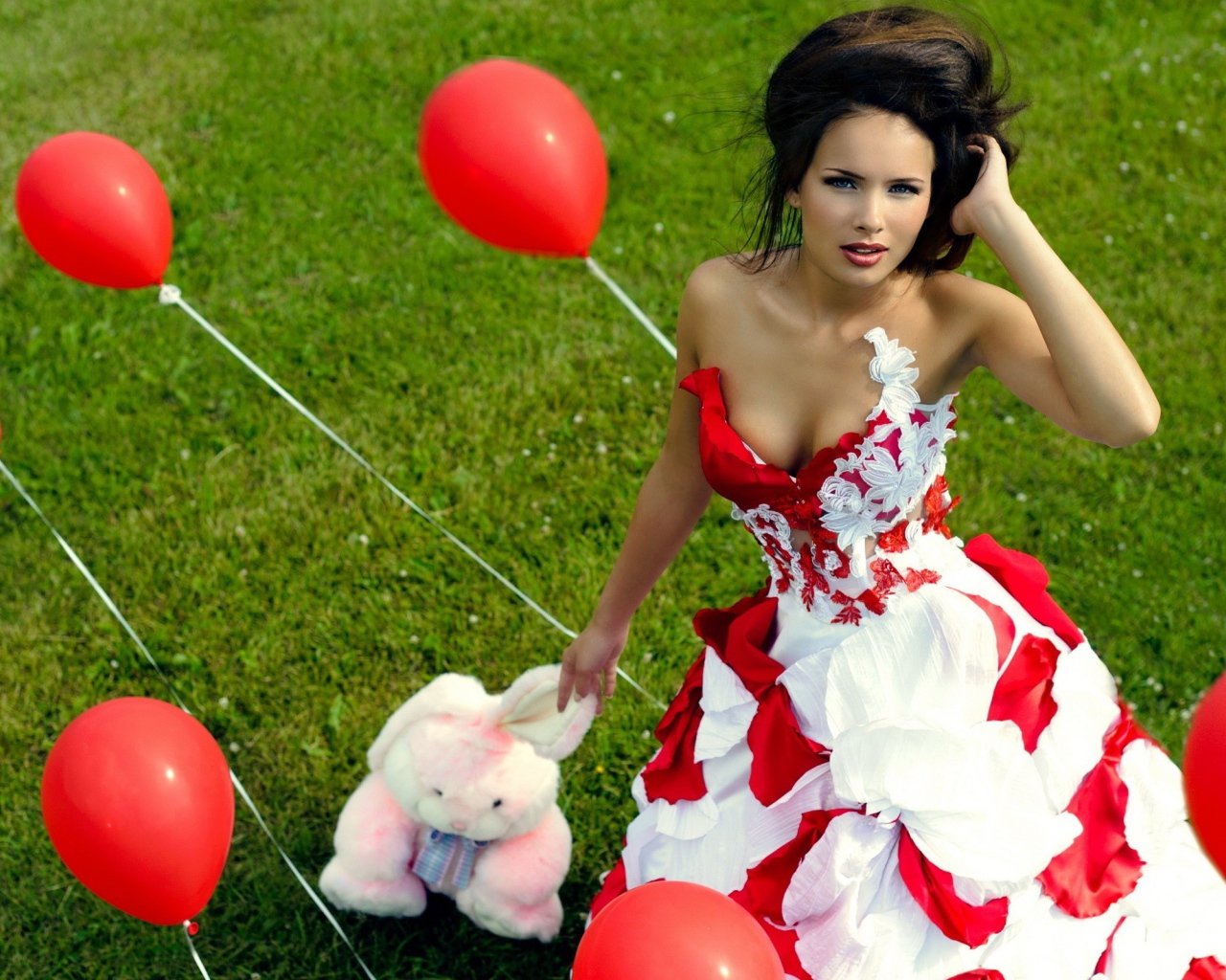 Девушка с игрушкой среди красных воздушных шариков