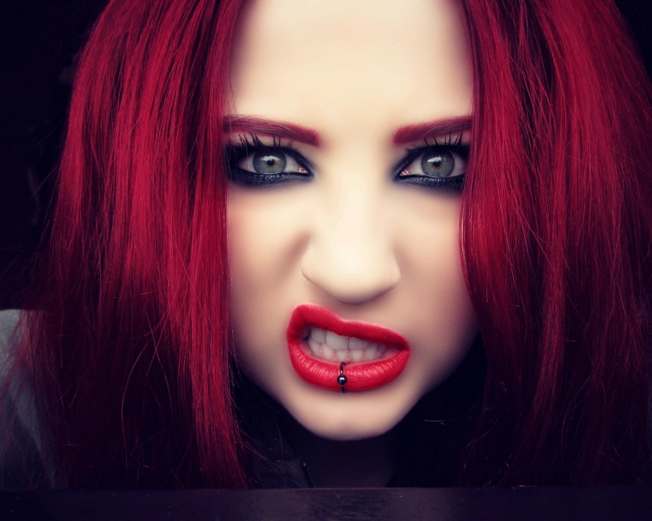 Девушка с красными волосами показывает зубы