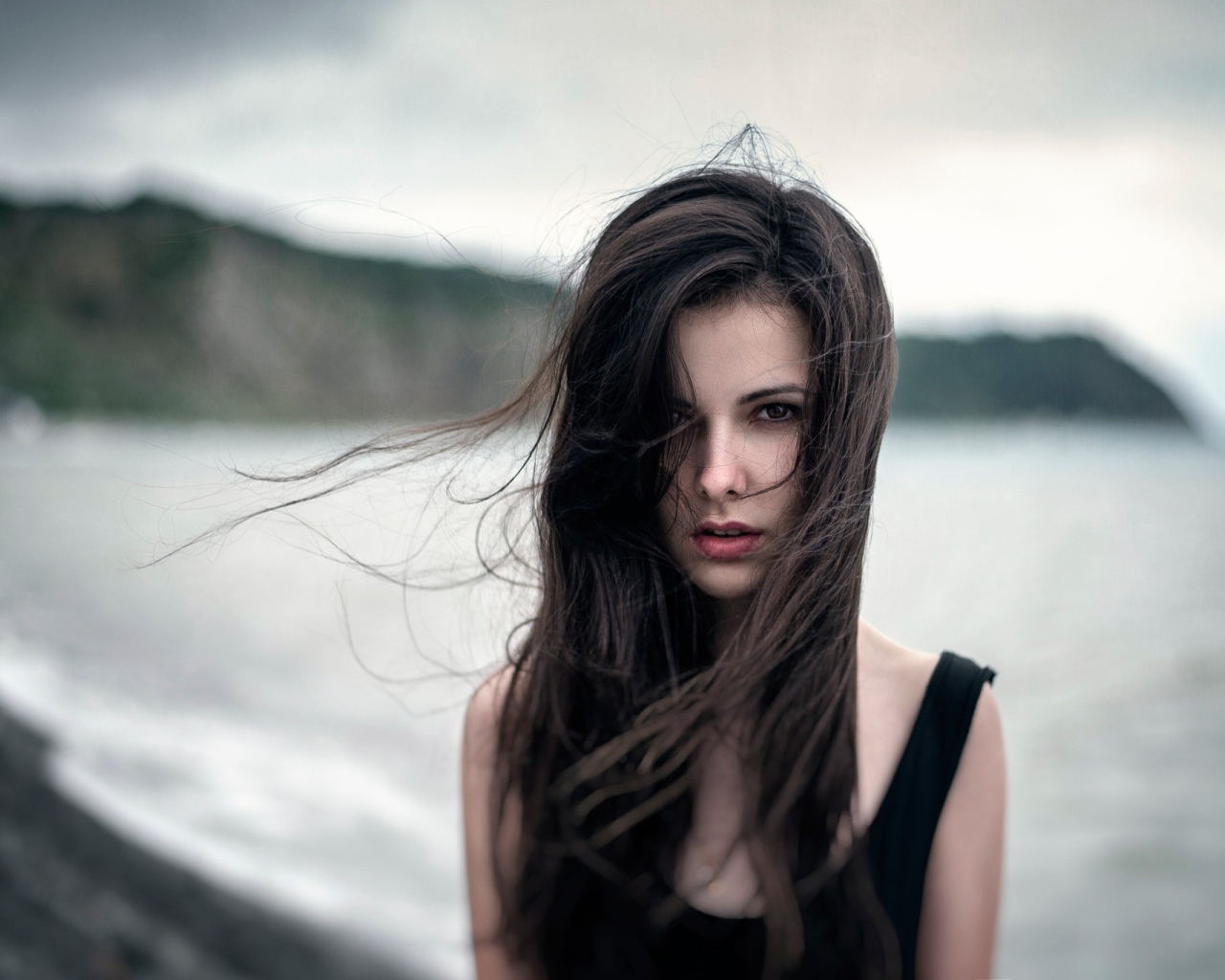 Ветер треплет волосы девушки у моря, портрет