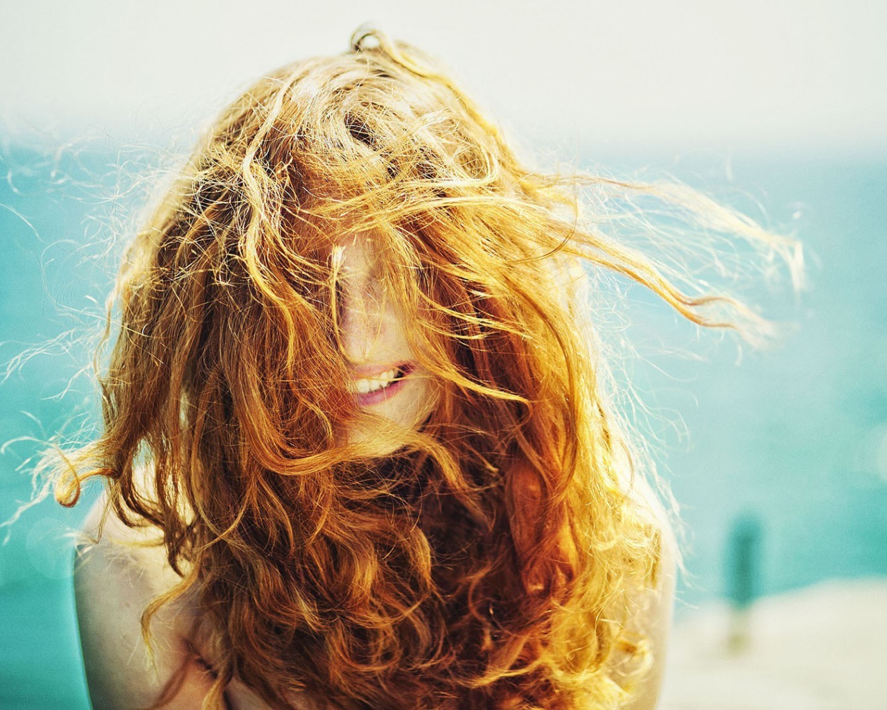 Ветер растрепал рыжие волосы у девушки