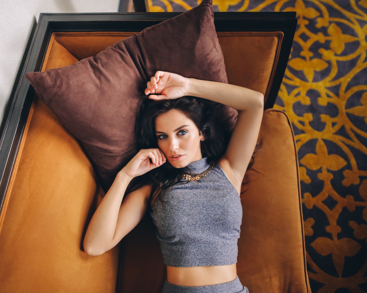 Модель Aurela Skandaj лежит на диване