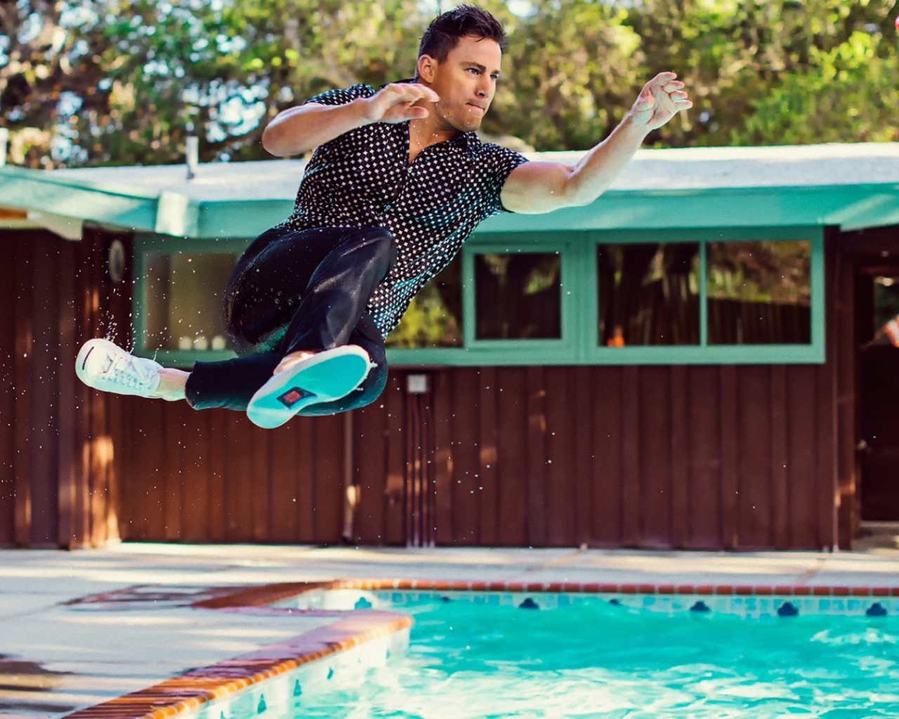 Мужчина прыгает в бассейн в одежде
