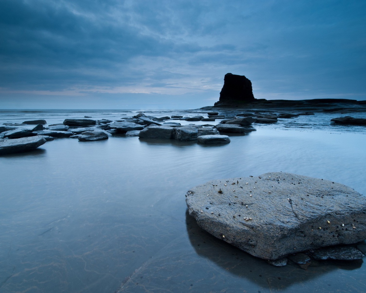Плоские камни в серой воде у берега