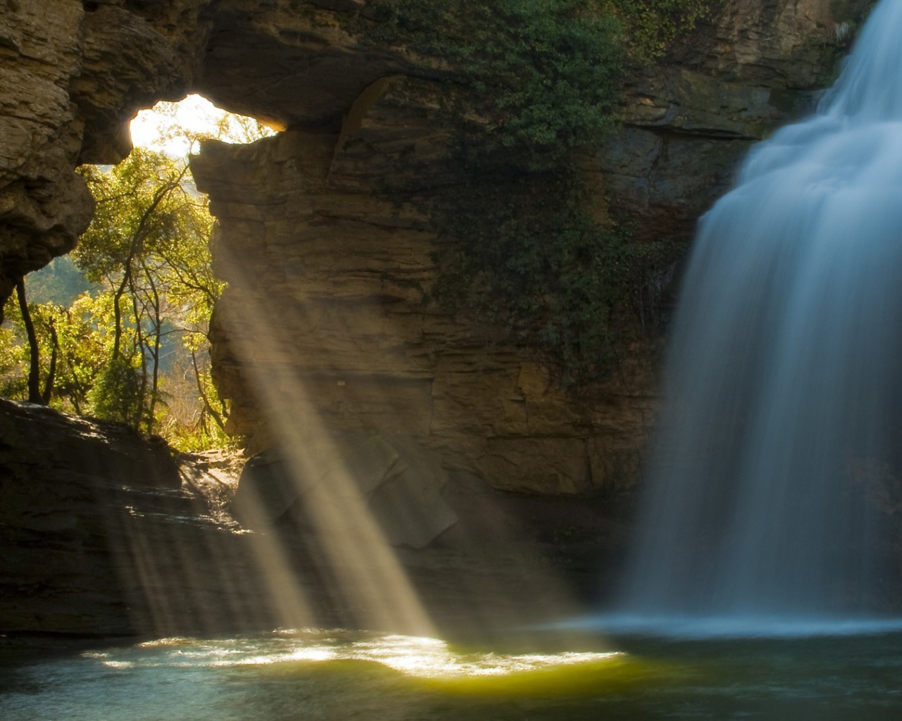Лучи солнца и вода падают в пещеру