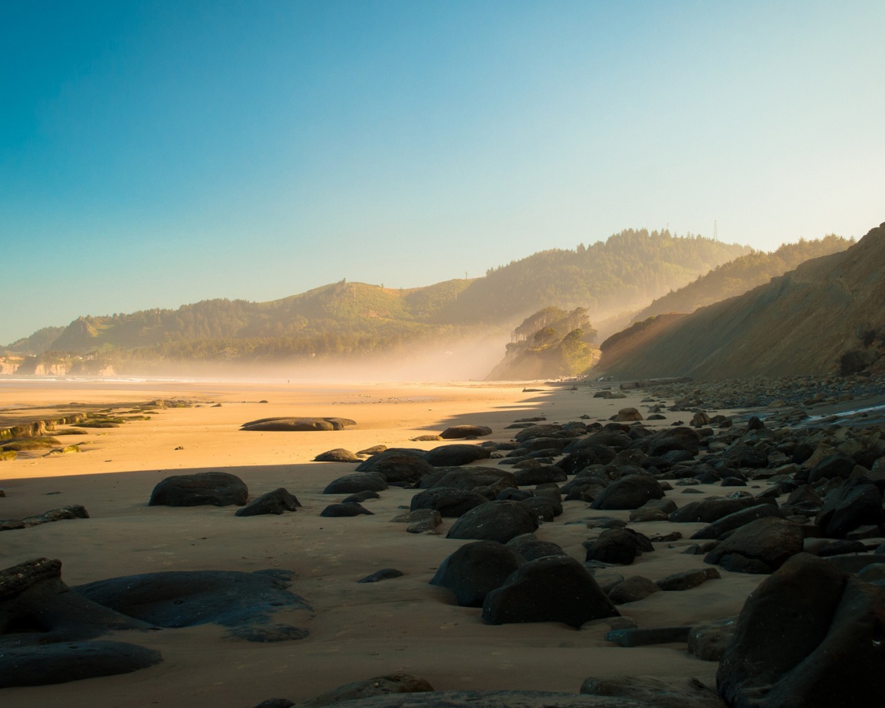 Черные круглые камни на песке пляжа