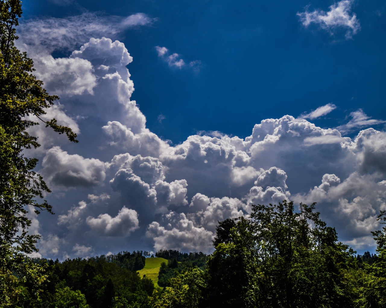 Кучевые облака над зелеными холмами