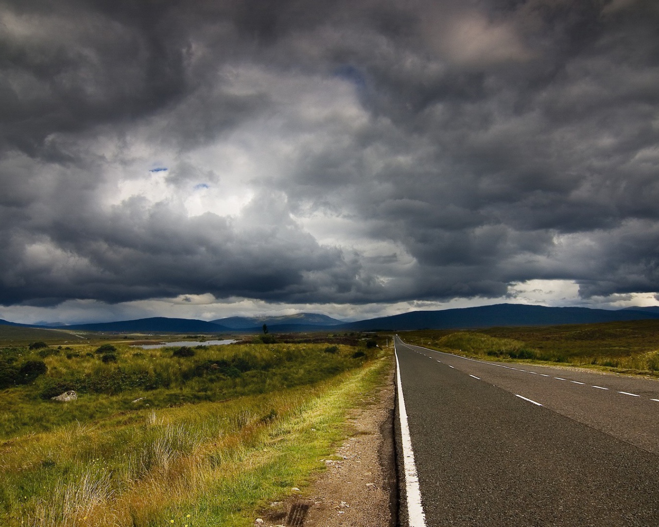 Шоссе среди полей под мрачными облаками