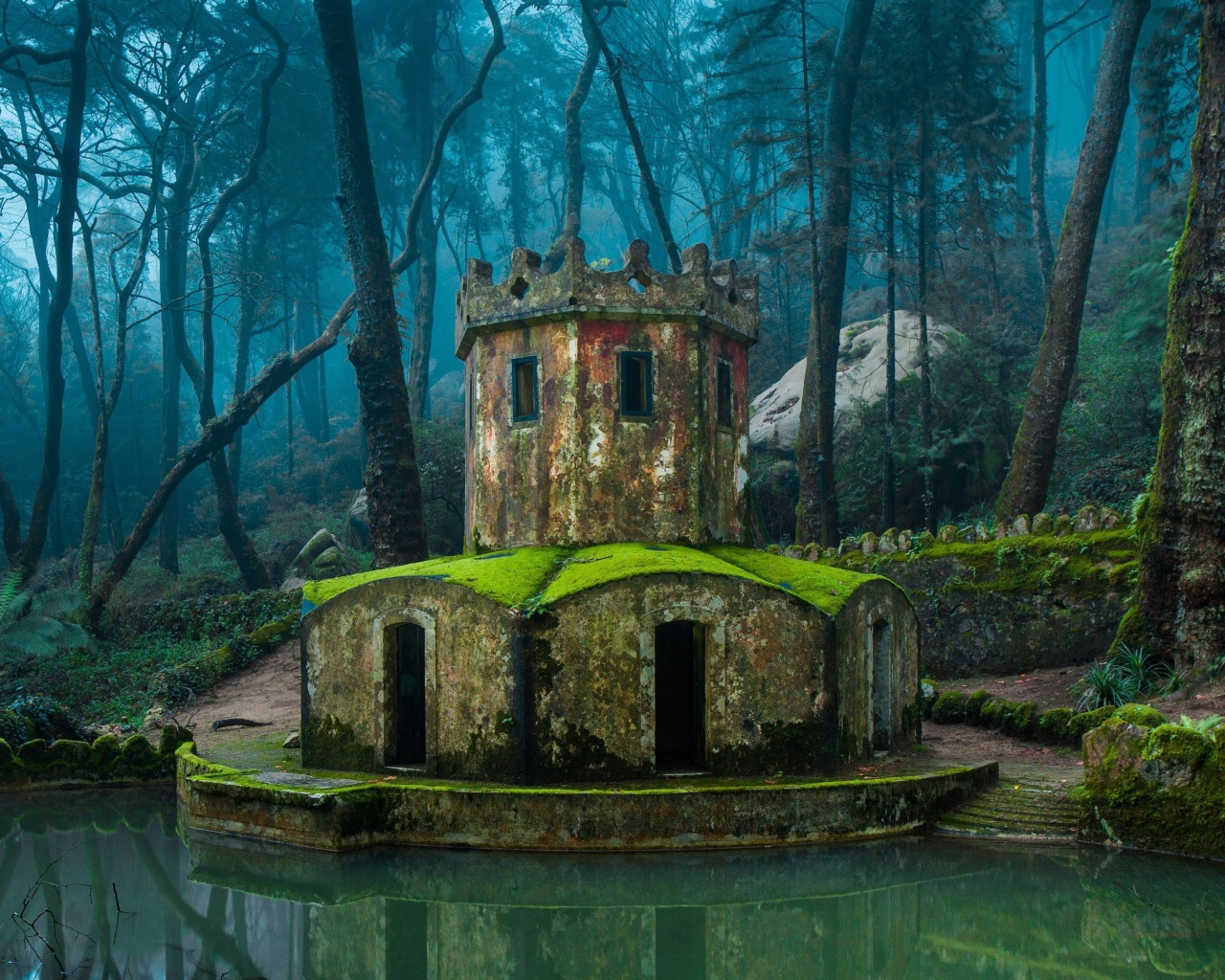 Покрытая мхом каменная беседка у воды