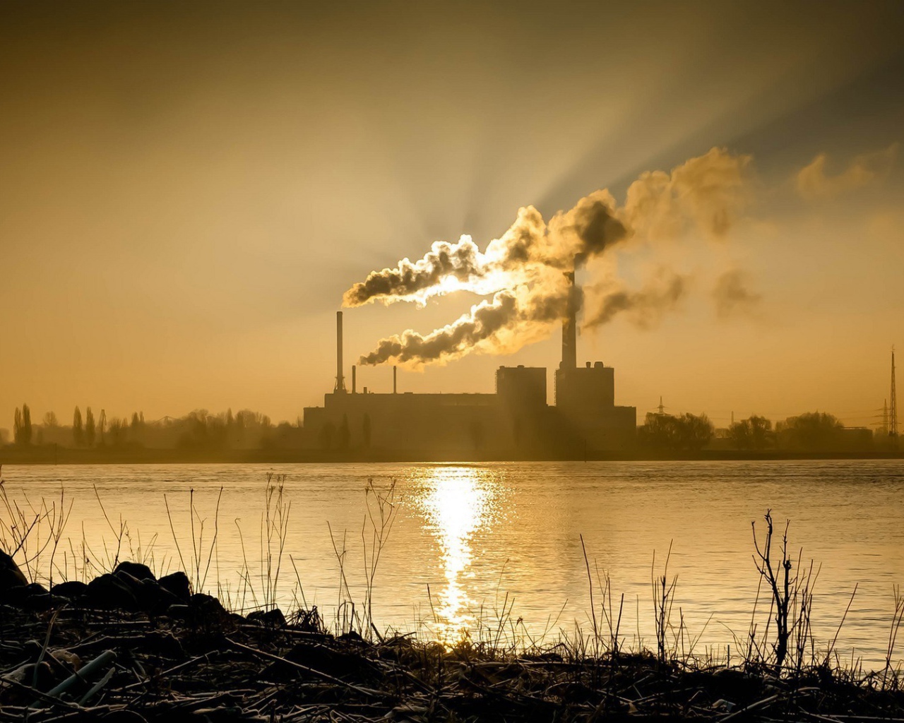 Лучи солнца пронизывают дым из заводских труб