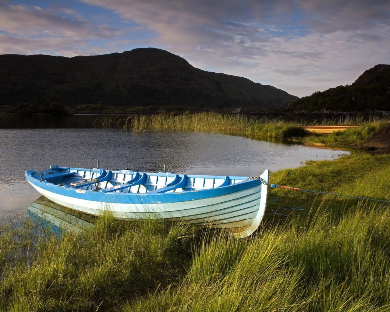 Синяя лодка на берегу озера