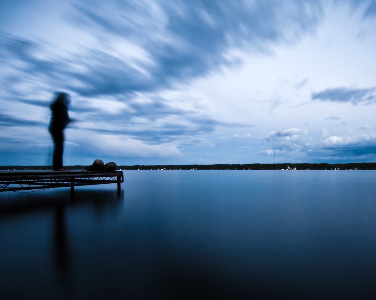 Силуэт человека на пристани у озера