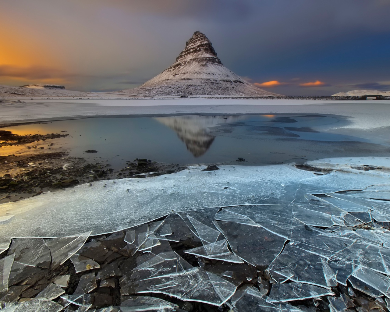 Тонкий лед озера на фоне горы