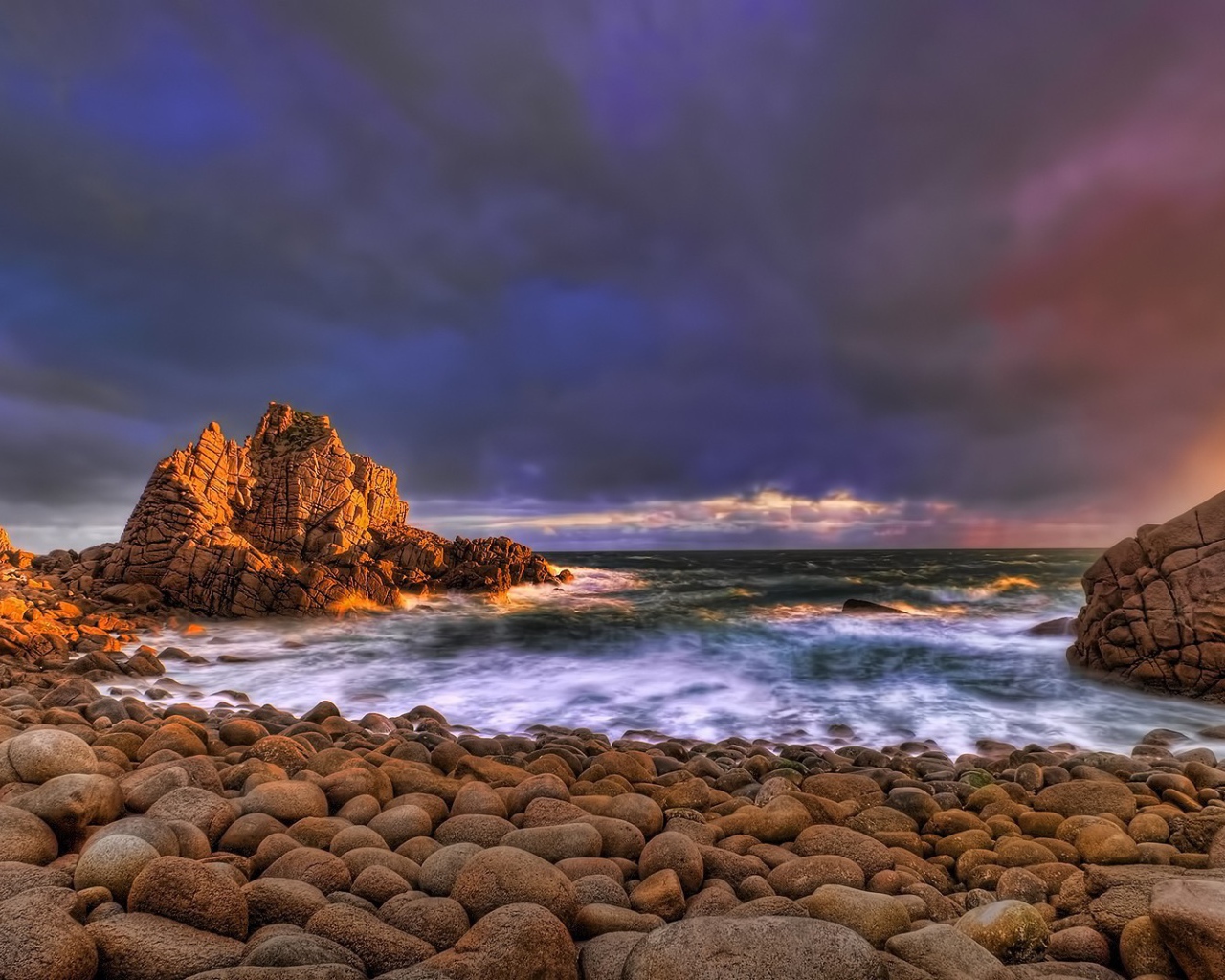 Большие гладкие камни на берегу бурного моря