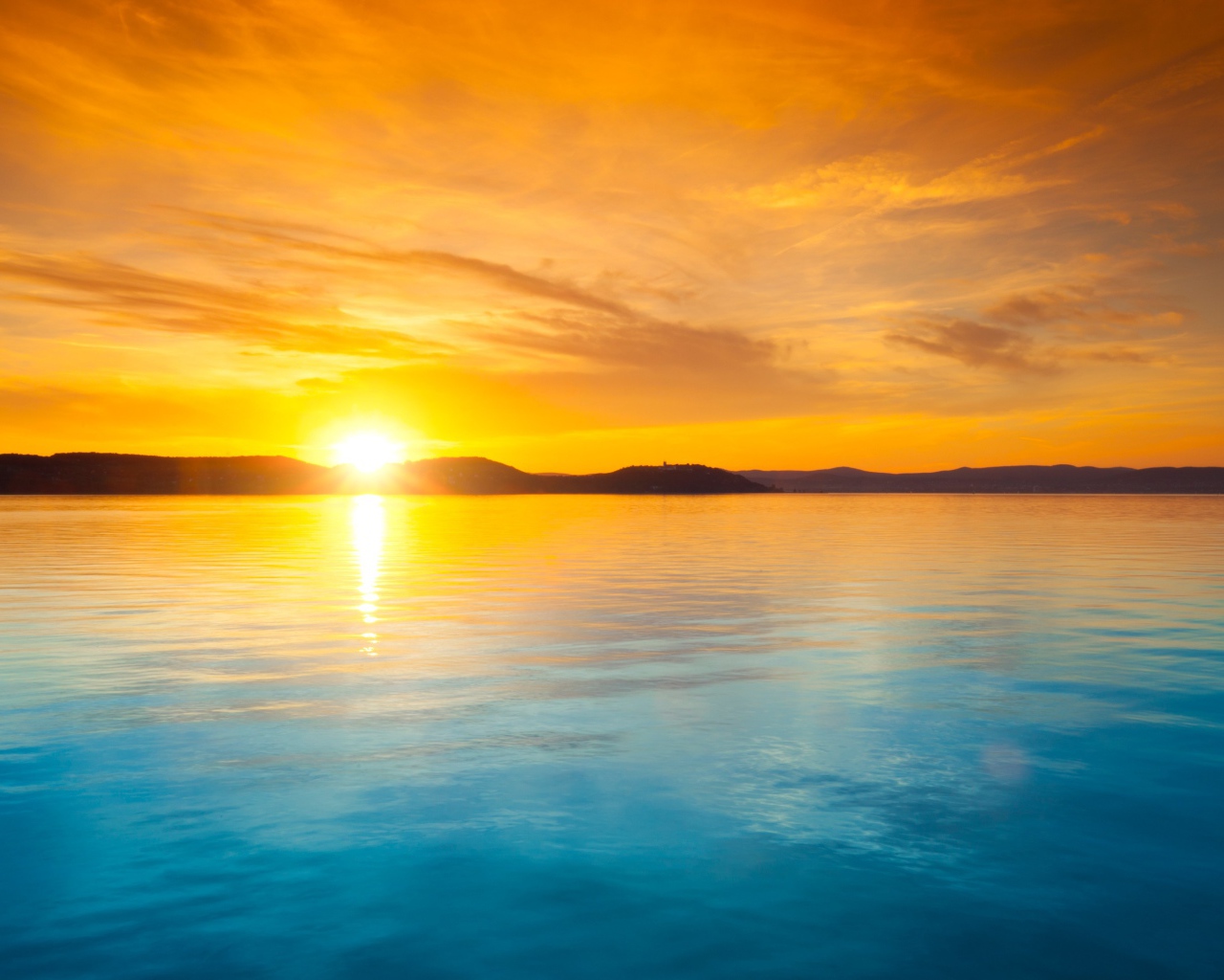 Оранжевое небо над голубой водой на закате