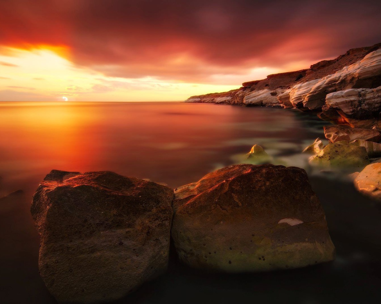 Два больших камня на берегу моря на закате