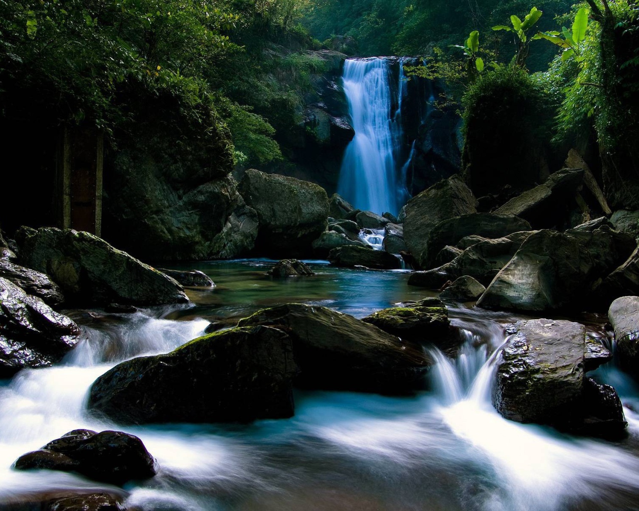 Голубой водопад позади камней на реке