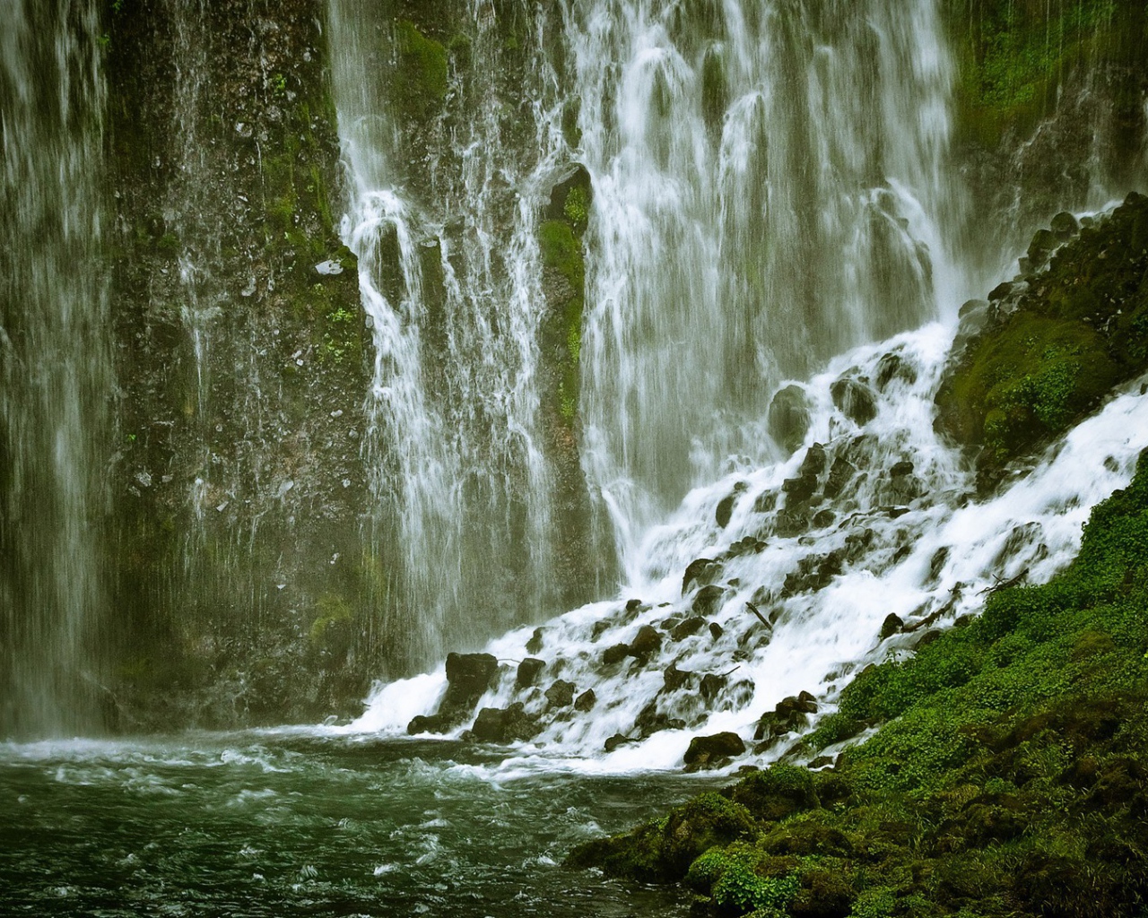 Брызги и потоки водопада среди зелени